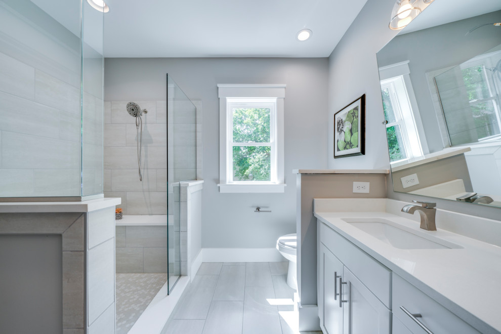 Photo of a mid-sized arts and crafts master bathroom in Raleigh with shaker cabinets, white cabinets, an open shower, a one-piece toilet, gray tile, ceramic tile, grey walls, ceramic floors, an undermount sink, engineered quartz benchtops, grey floor, an open shower and white benchtops.