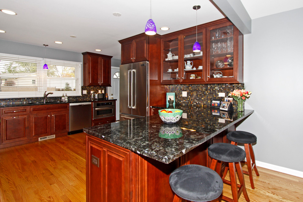 Example of a mid-sized transitional u-shaped medium tone wood floor eat-in kitchen design in Chicago with an undermount sink, raised-panel cabinets, medium tone wood cabinets, granite countertops, multicolored backsplash, glass tile backsplash, stainless steel appliances and a peninsula