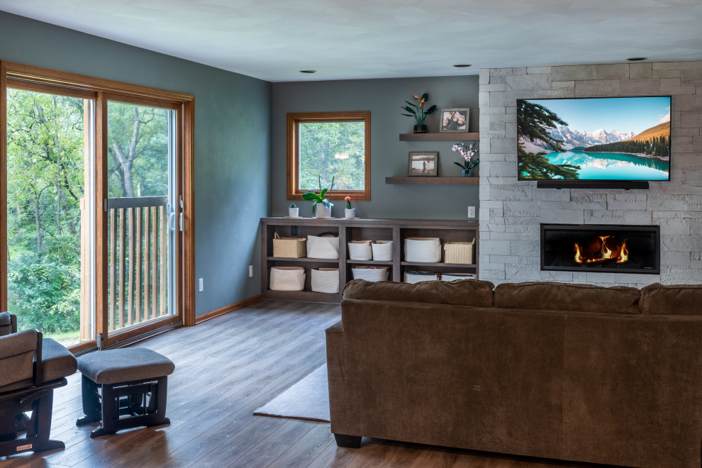 Mittelgroßes, Offenes Modernes Wohnzimmer mit grüner Wandfarbe, Vinylboden, Kamin, Kaminumrandung aus gestapelten Steinen und TV-Wand in Sonstige