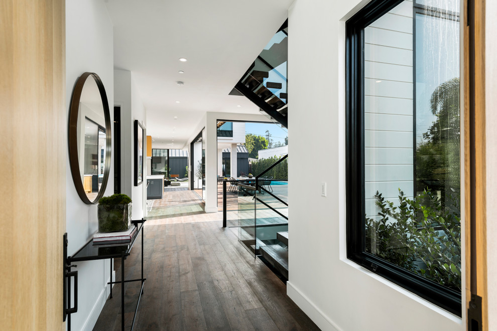 Photo of a large beach style vestibule in Los Angeles with white walls, light hardwood floors, a single front door and brown floor.