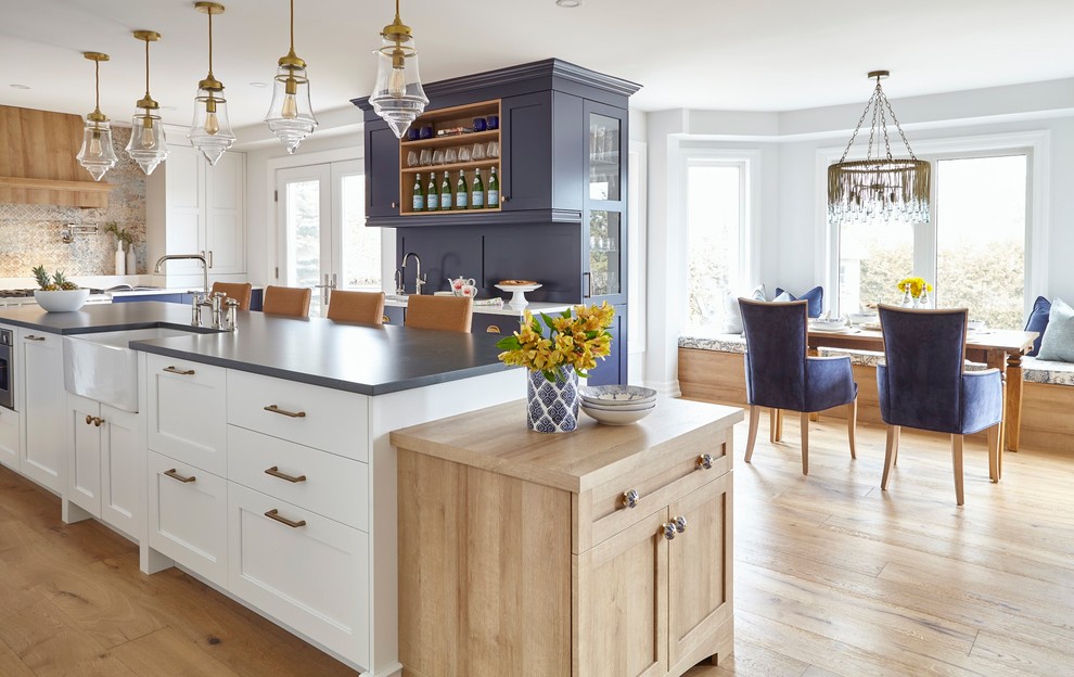 Photo of an expansive transitional u-shaped eat-in kitchen in Toronto with an undermount sink, shaker cabinets, blue cabinets, quartz benchtops, panelled appliances, light hardwood floors, with island, brown floor and blue benchtop.