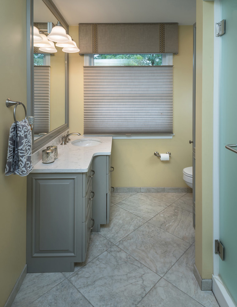Design ideas for a mid-sized traditional master bathroom in Other with raised-panel cabinets, green cabinets, an alcove shower, yellow walls, porcelain floors, an undermount sink, solid surface benchtops, grey floor and a hinged shower door.