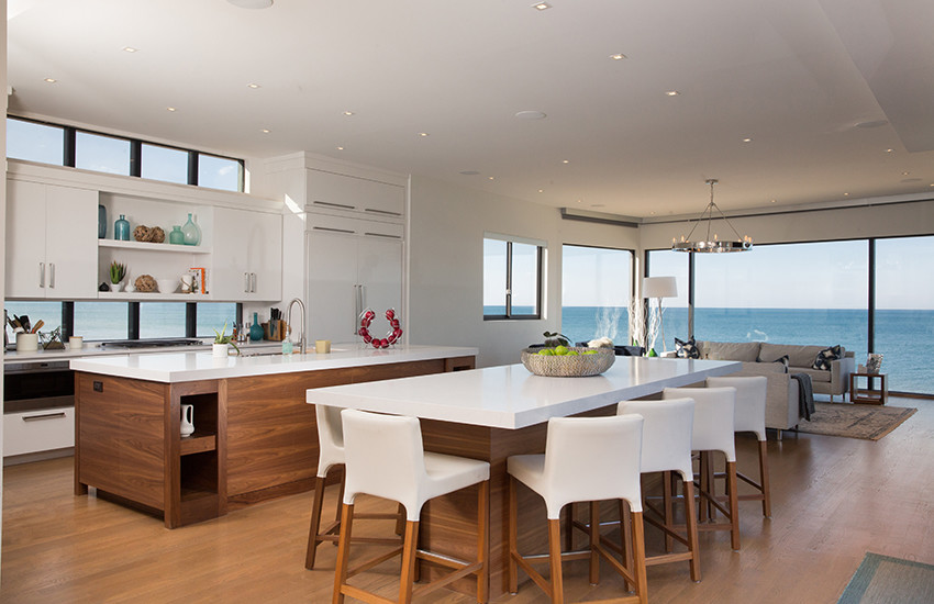 Expansive modern l-shaped open plan kitchen in Chicago with a double-bowl sink, flat-panel cabinets, white cabinets, quartz benchtops, white splashback, panelled appliances, light hardwood floors and multiple islands.