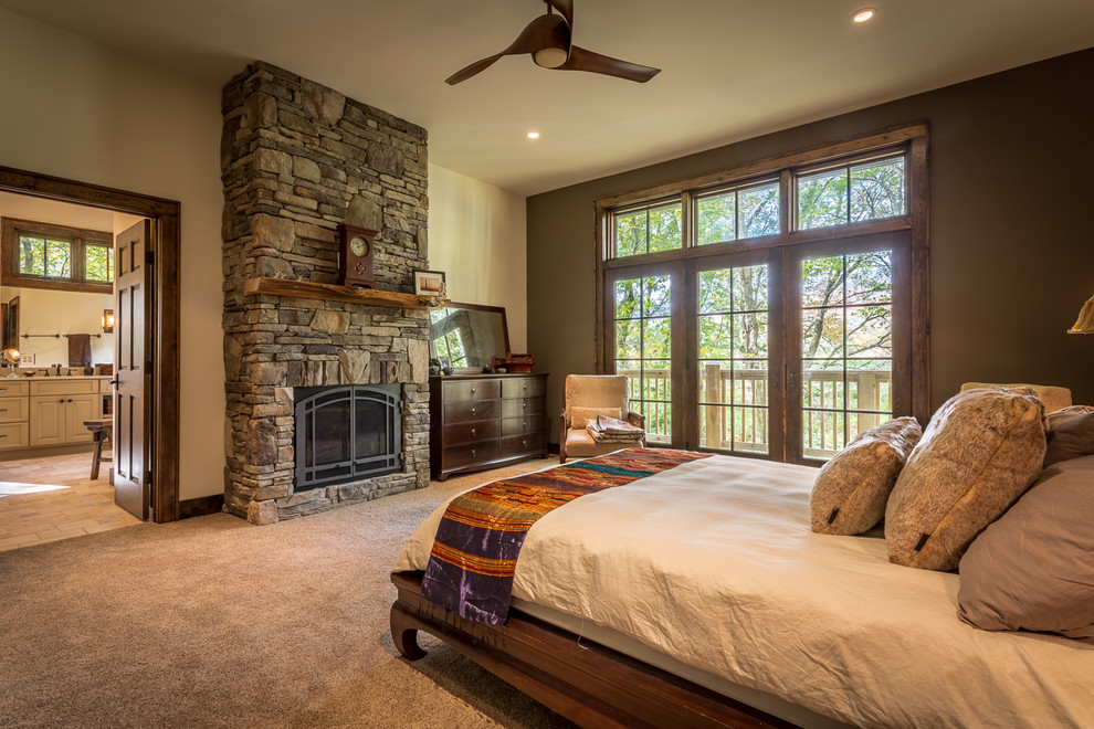 This is an example of a large country master bedroom in Charlotte with green walls, carpet, a standard fireplace and a stone fireplace surround.