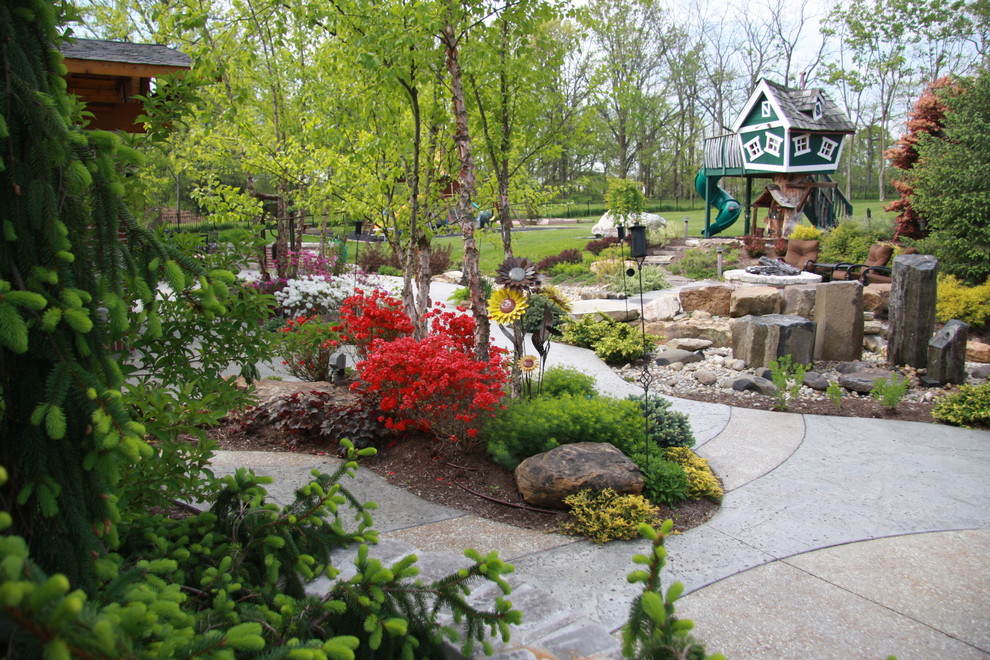 Large country backyard garden in Indianapolis with with outdoor playset and concrete pavers.