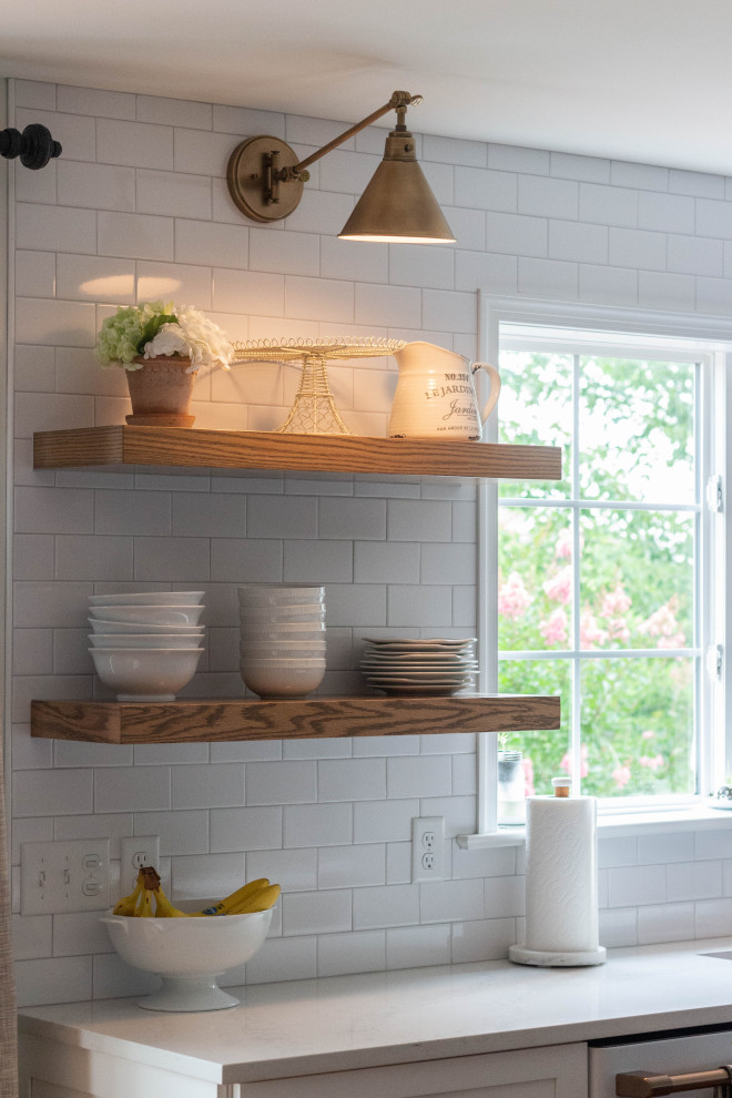 Mid-sized transitional l-shaped medium tone wood floor and brown floor open concept kitchen photo with an undermount sink, shaker cabinets, white cabinets, quartzite countertops, white backsplash, ceramic backsplash, white appliances, an island and white countertops