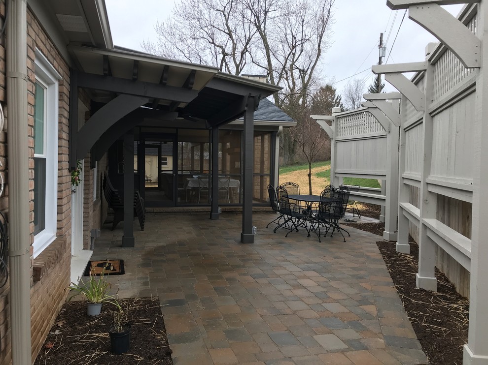 This is an example of a mid-sized traditional backyard verandah in Other with concrete pavers and a roof extension.