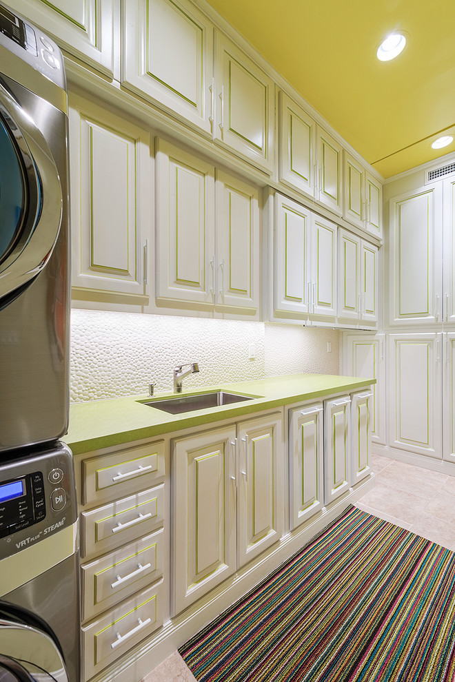 This is an example of a tropical dedicated laundry room in Los Angeles with an undermount sink, raised-panel cabinets, white cabinets, beige floor and green benchtop.