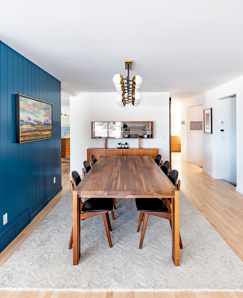 Immagine di una sala da pranzo aperta verso la cucina minimalista di medie dimensioni con pareti blu, parquet chiaro e pareti in perlinato