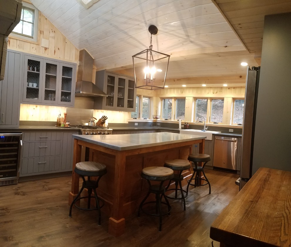 Photo of a mid-sized country u-shaped eat-in kitchen in Boston with a farmhouse sink, recessed-panel cabinets, grey cabinets, soapstone benchtops, grey splashback, slate splashback, stainless steel appliances and dark hardwood floors.