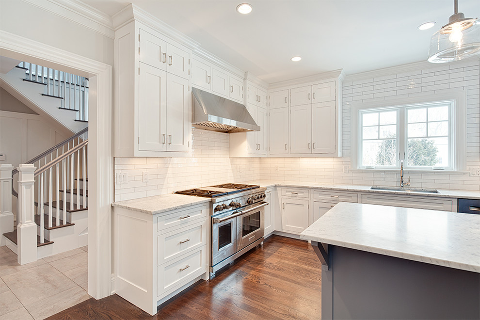Eat-in kitchen - large transitional u-shaped dark wood floor and brown floor eat-in kitchen idea with an undermount sink, shaker cabinets, white cabinets, white backsplash, stainless steel appliances and an island