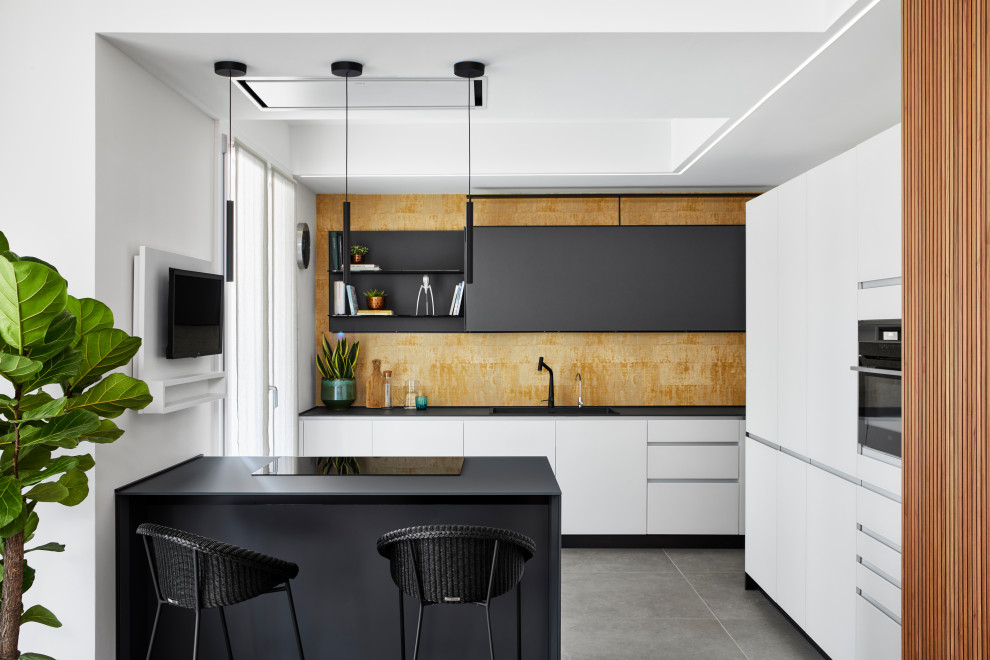 Photo of a mid-sized contemporary l-shaped eat-in kitchen in Milan with a double-bowl sink, flat-panel cabinets, grey cabinets, glass benchtops, yellow splashback, porcelain floors, with island, grey floor, grey benchtop and recessed.