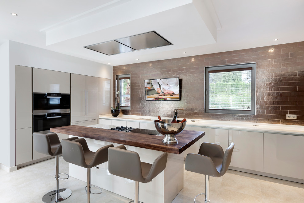 Photo of a large contemporary l-shaped open plan kitchen in Other with flat-panel cabinets, beige cabinets, brown splashback, black appliances, with island and beige floor.