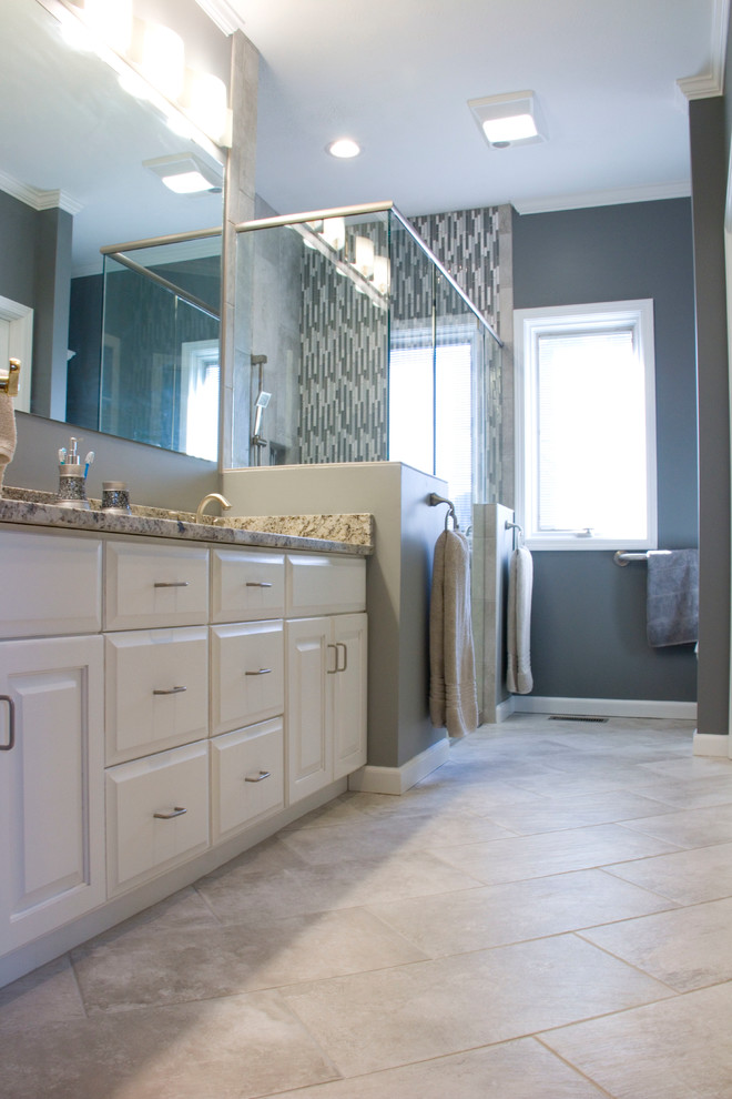 Walk-in shower - mid-sized transitional master gray tile and ceramic tile ceramic tile walk-in shower idea with an undermount sink, raised-panel cabinets, white cabinets, granite countertops, a two-piece toilet and gray walls