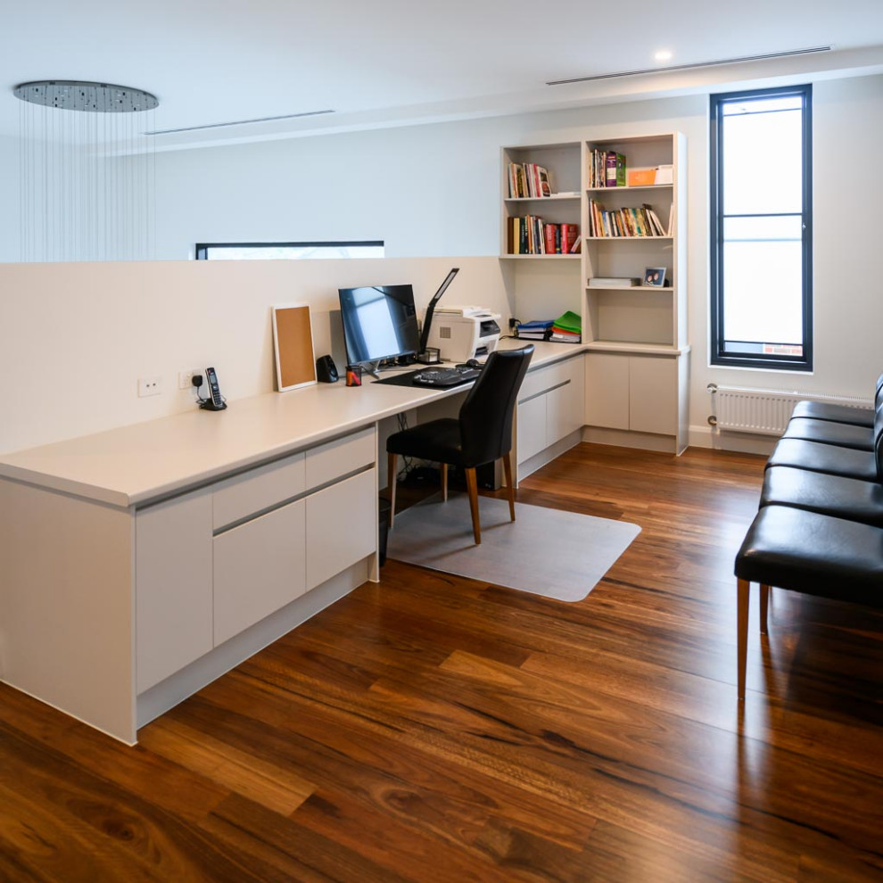 Пример оригинального дизайна: кабинет среднего размера в стиле модернизм с белыми стенами, паркетным полом среднего тона и встроенным рабочим столом