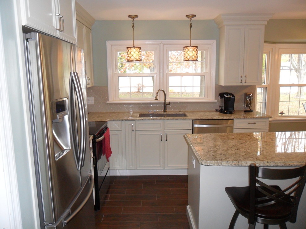 Transitional l-shaped ceramic tile kitchen photo in St Louis with an undermount sink, recessed-panel cabinets, white cabinets, gray backsplash, stainless steel appliances and an island