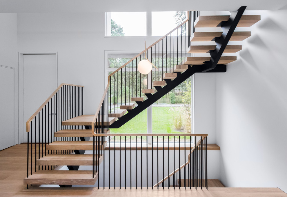 Inspiration for a large modern wood u-shaped staircase in New York with open risers and metal railing.
