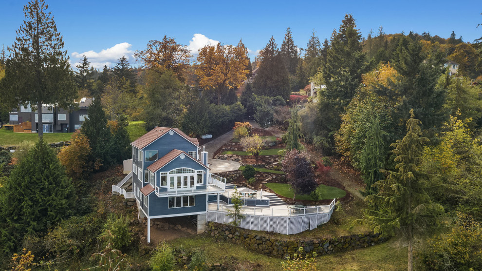 Стильный дизайн: большой, трехэтажный, деревянный, синий частный загородный дом в стиле неоклассика (современная классика) с двускатной крышей, черепичной крышей, красной крышей и отделкой планкеном - последний тренд