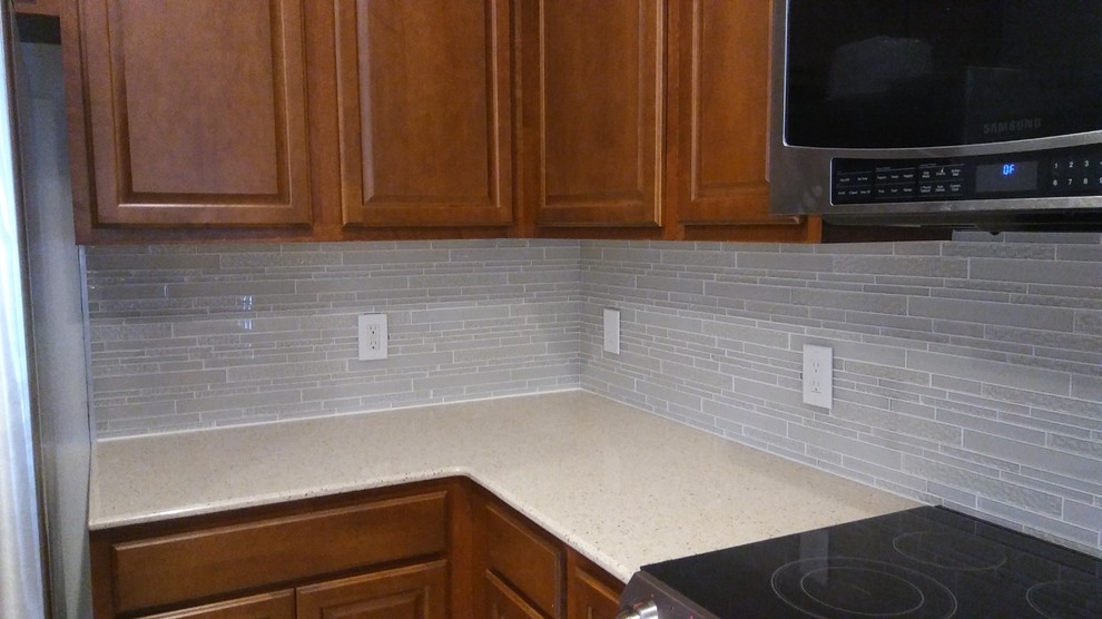 Eat-in kitchen - mid-sized transitional l-shaped eat-in kitchen idea with quartz countertops, white backsplash, glass tile backsplash and a peninsula