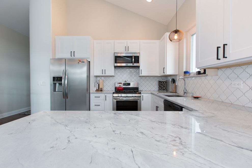 Inspiration for a mid-sized transitional u-shaped open plan kitchen in Chicago with an undermount sink, shaker cabinets, white cabinets, marble benchtops, white splashback, ceramic splashback, stainless steel appliances, dark hardwood floors and a peninsula.