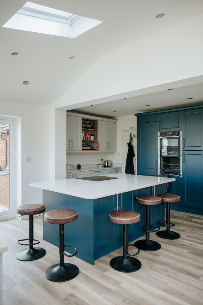 Diseño de cocina minimalista grande con armarios estilo shaker, puertas de armario azules, encimera de granito, salpicadero verde, puertas de granito, electrodomésticos con paneles, una isla y encimeras grises