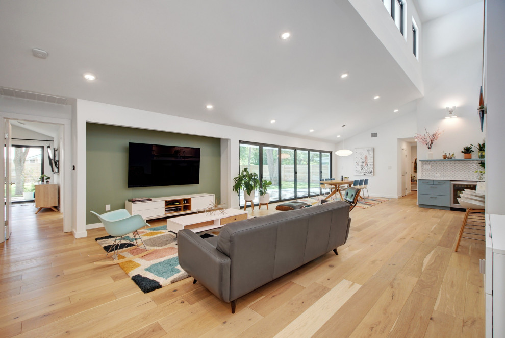 Foto di un grande soggiorno nordico aperto con angolo bar, pareti verdi, parquet chiaro, TV a parete, pavimento marrone e soffitto a volta