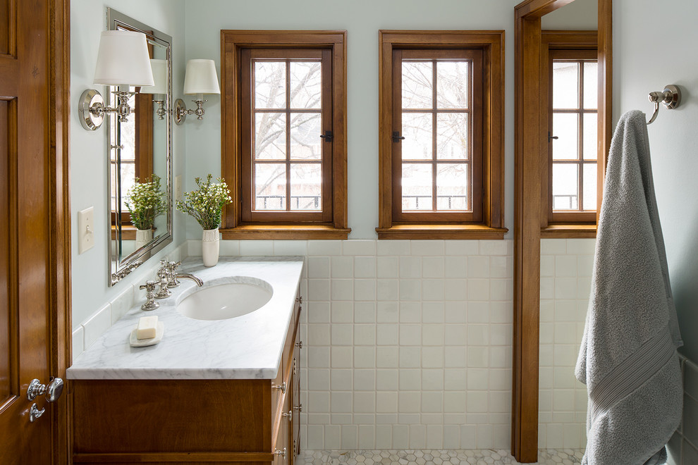 Photo of a traditional bathroom in Minneapolis with medium wood cabinets, white tile, white walls, mosaic tile floors and an undermount sink.