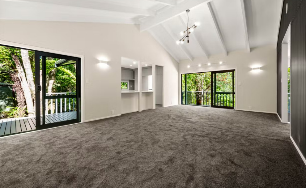 Aménagement d'un grand salon mansardé ou avec mezzanine moderne avec un mur blanc, moquette, un sol gris, poutres apparentes et du lambris.