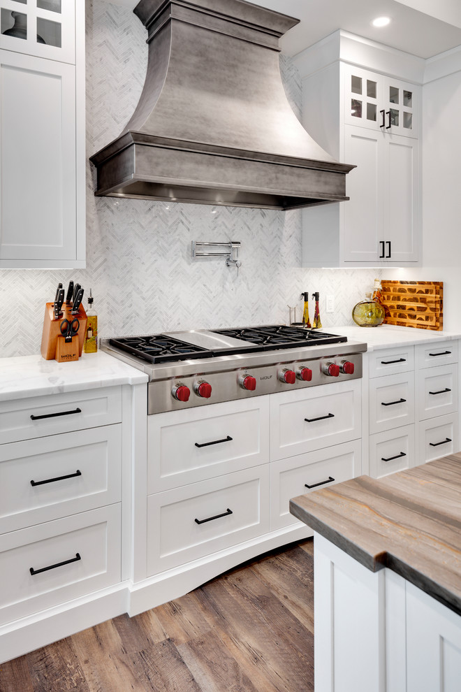 Huge transitional u-shaped dark wood floor and brown floor kitchen photo in Calgary with shaker cabinets, white cabinets, marble countertops, white backsplash, marble backsplash, stainless steel appliances, an island and white countertops