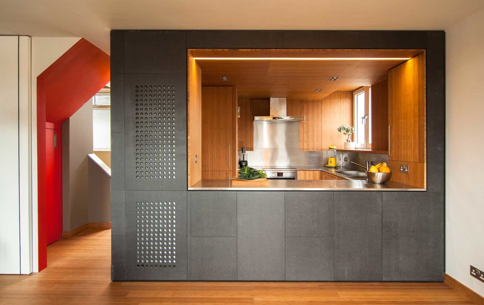 Inspiration for a small contemporary u-shaped eat-in kitchen in London with a drop-in sink, stainless steel benchtops, metallic splashback, stainless steel appliances and bamboo floors.