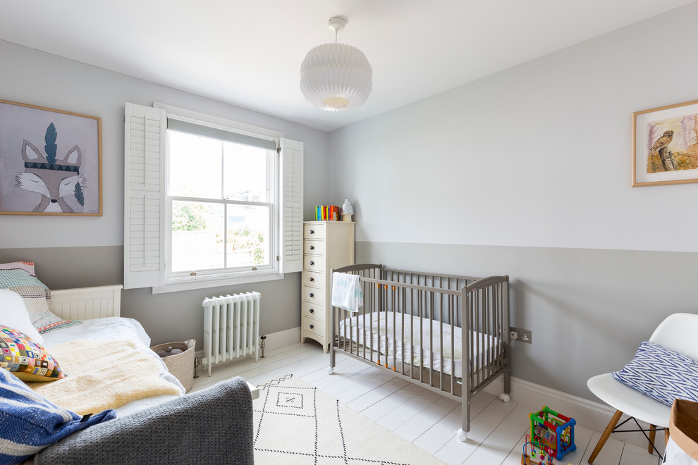 This is an example of a transitional gender-neutral nursery in London with grey walls, painted wood floors and white floor.