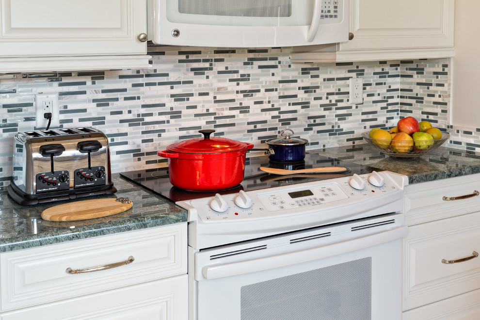 Inspiration for a mid-sized transitional galley eat-in kitchen remodel in Miami with raised-panel cabinets, white cabinets, granite countertops, multicolored backsplash, an undermount sink, matchstick tile backsplash and white appliances