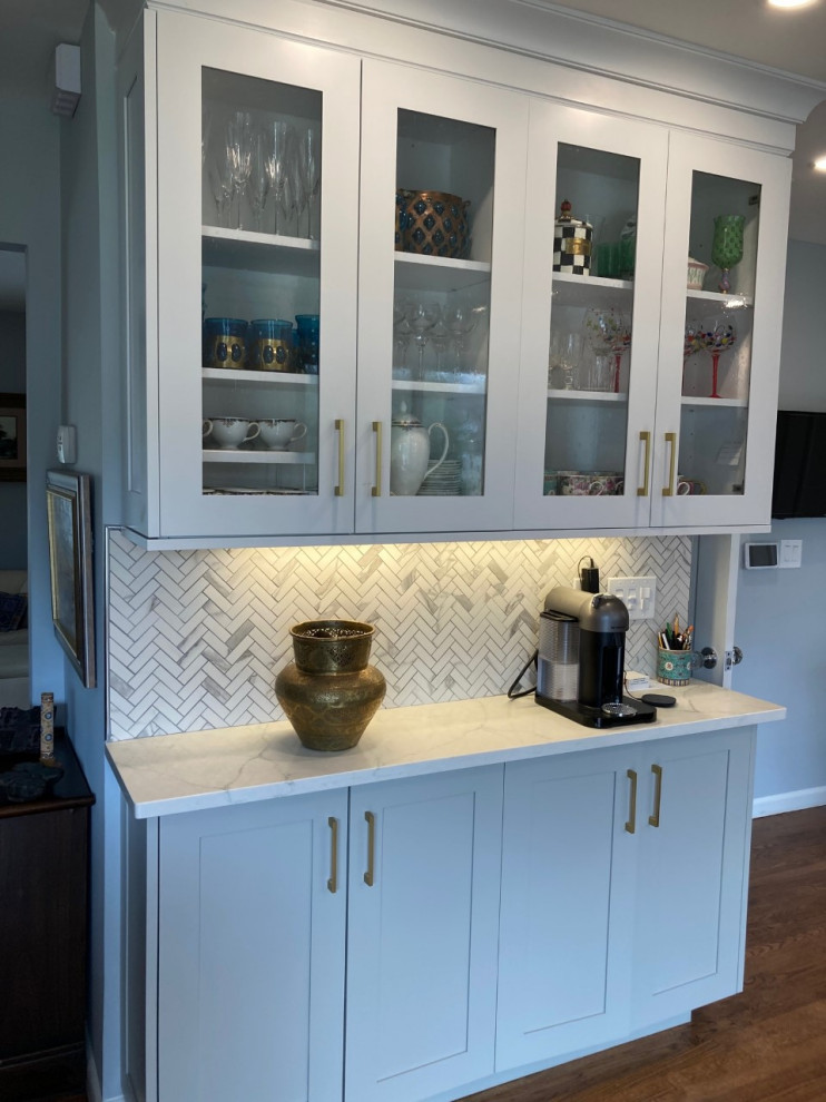 This is an example of a large transitional l-shaped eat-in kitchen in New York with a farmhouse sink, shaker cabinets, white cabinets, stainless steel appliances, medium hardwood floors, no island, brown floor and white benchtop.