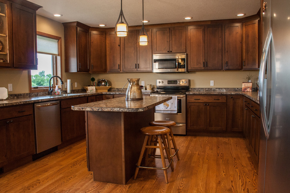 This is an example of a mid-sized arts and crafts u-shaped kitchen in Other with with island, an undermount sink, recessed-panel cabinets, medium wood cabinets, stainless steel appliances and medium hardwood floors.