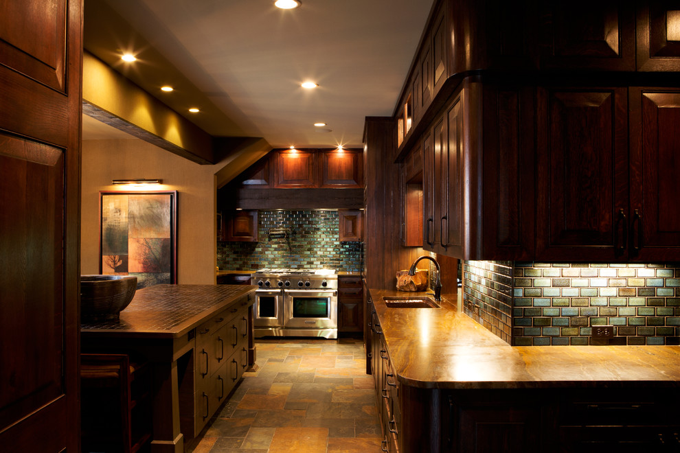Large transitional l-shaped slate floor and brown floor eat-in kitchen photo with an undermount sink, recessed-panel cabinets, dark wood cabinets, granite countertops, ceramic backsplash, stainless steel appliances, an island and multicolored backsplash