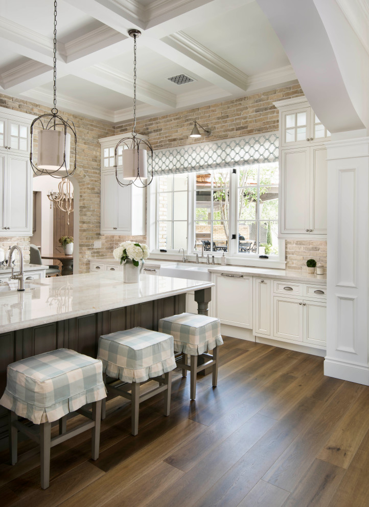 Inspiration for an u-shaped open plan kitchen in Phoenix with white cabinets, quartzite benchtops, brick splashback, medium hardwood floors, with island and recessed-panel cabinets.