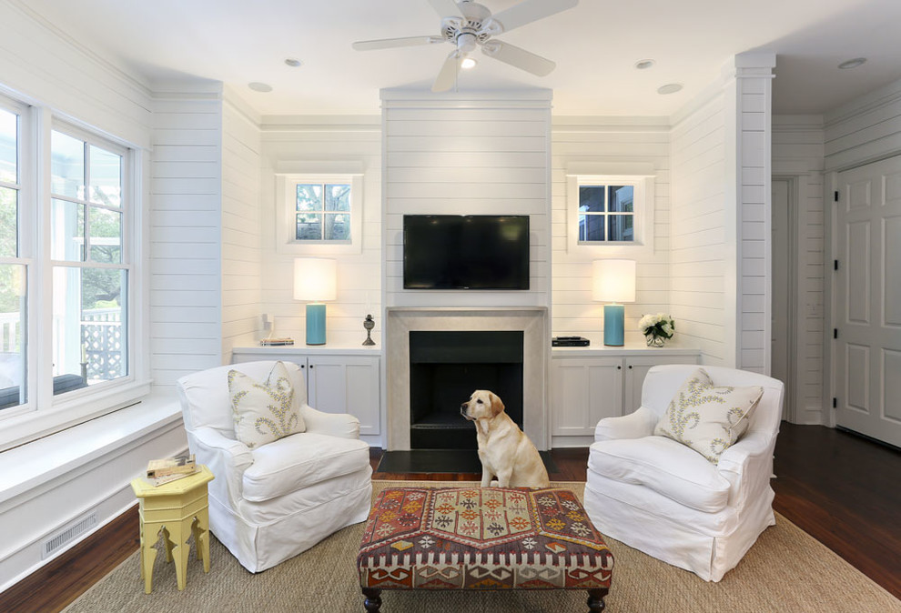 This is an example of a beach style living room in Charleston with white walls, dark hardwood floors, a standard fireplace and a wall-mounted tv.