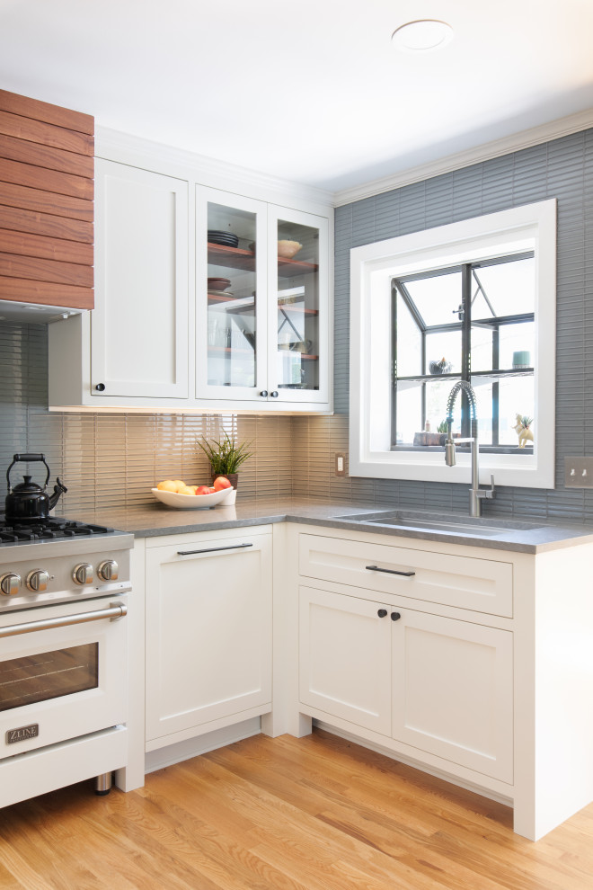 Inspiration for a mid-sized transitional u-shaped light wood floor and brown floor eat-in kitchen remodel in Austin with an undermount sink, shaker cabinets, white cabinets, quartz countertops, blue backsplash, glass tile backsplash, stainless steel appliances, no island and gray countertops
