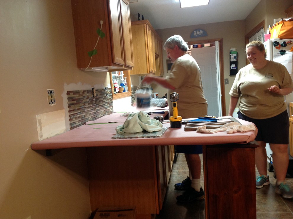 Eat-in kitchen - l-shaped eat-in kitchen idea with an undermount sink, flat-panel cabinets, brown backsplash, glass tile backsplash, stainless steel appliances and a peninsula
