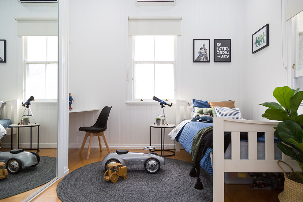 This is an example of a contemporary kids' bedroom for kids 4-10 years old and boys in Other with white walls, medium hardwood floors and beige floor.