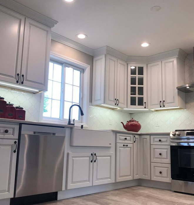 Traditional kitchen/diner in New York with a belfast sink, raised-panel cabinets, turquoise cabinets, engineered stone countertops, white splashback, ceramic splashback, stainless steel appliances, porcelain flooring and white worktops.