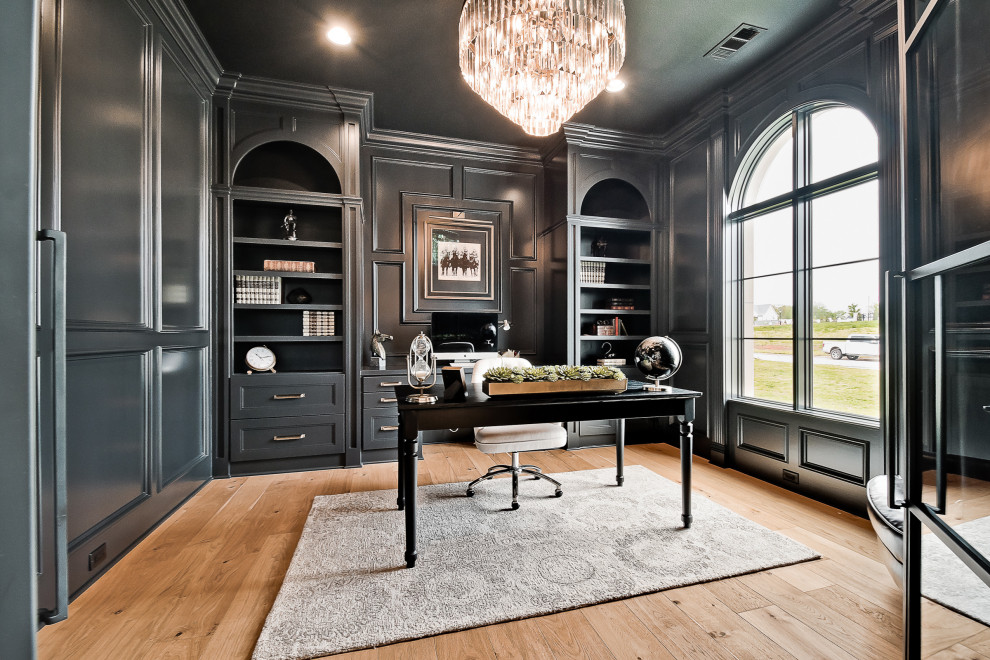 Inspiration for a large transitional study room in Other with black walls, light hardwood floors, a built-in desk and panelled walls.