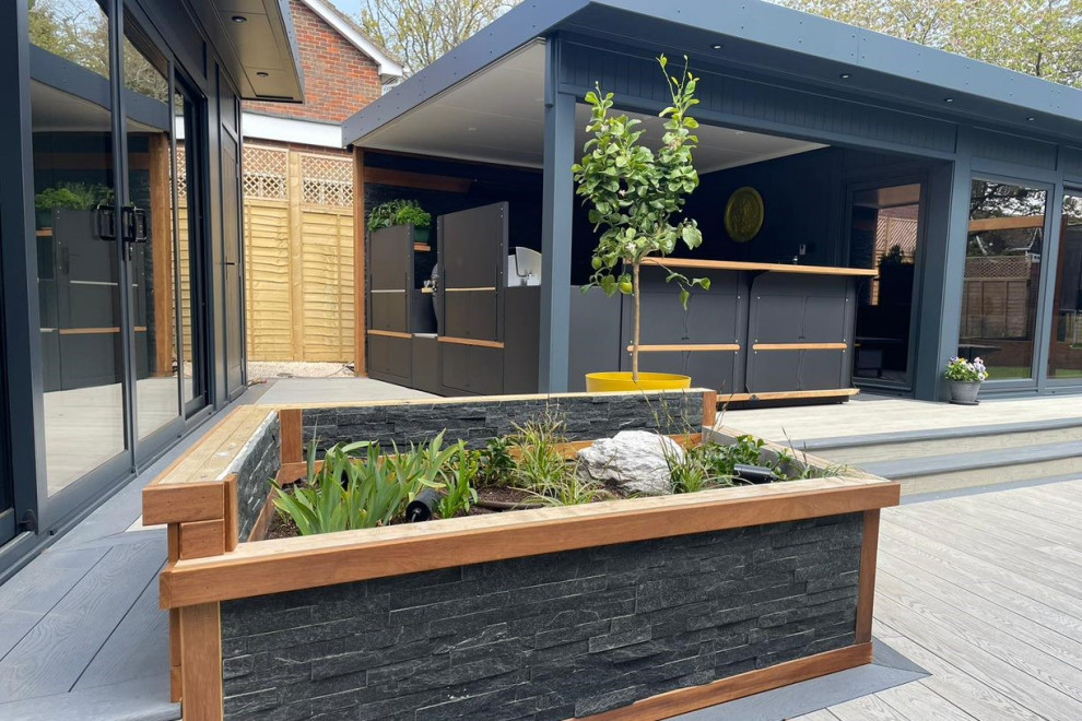 Inspiration for a large modern back ground level terrace in Hertfordshire with an outdoor kitchen and a roof extension.