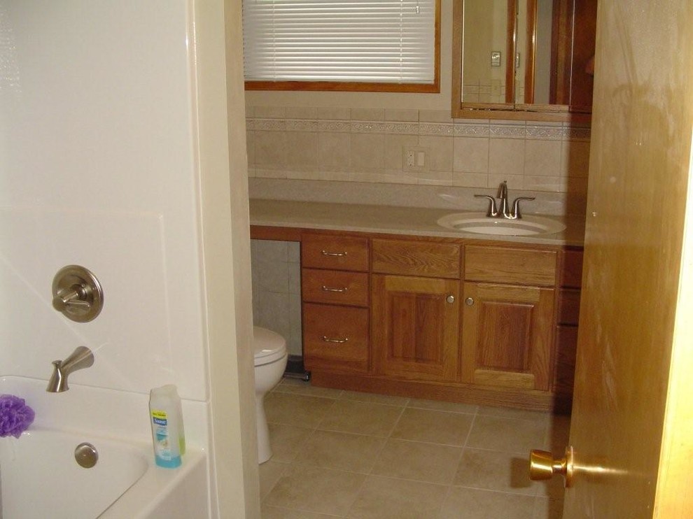Small country bathroom in Other with medium wood cabinets, an alcove tub, a shower/bathtub combo, a two-piece toilet and onyx benchtops.