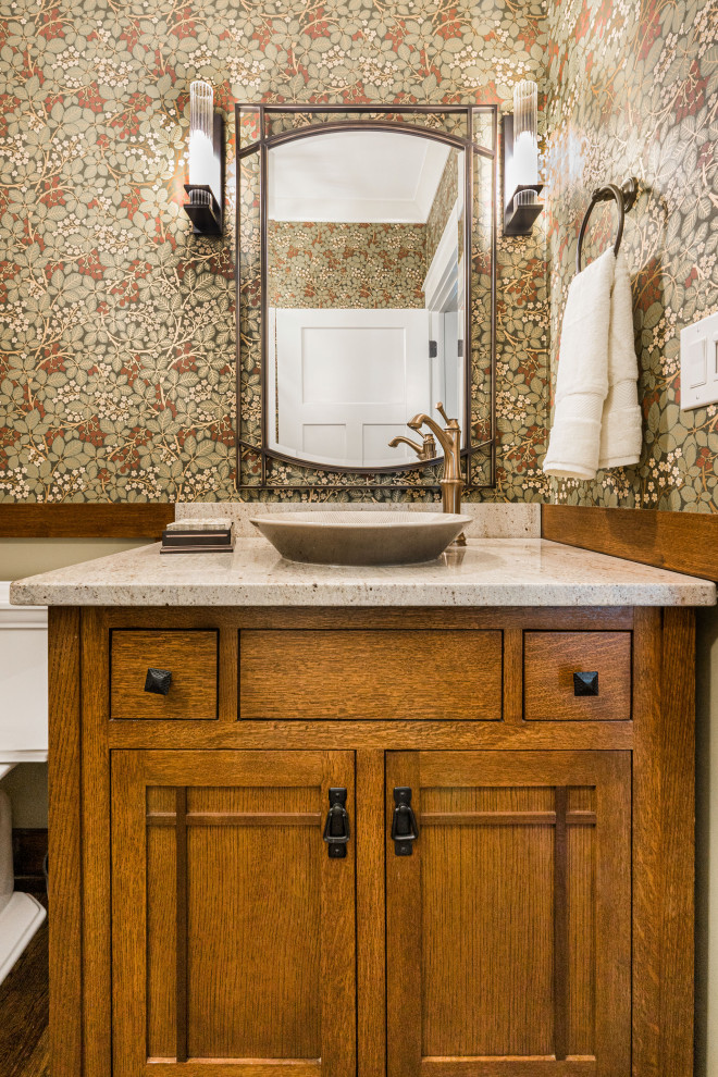 Medium sized classic cloakroom in Chicago with freestanding cabinets, medium wood cabinets, a two-piece toilet, multi-coloured walls, medium hardwood flooring, a vessel sink, engineered stone worktops, brown floors, beige worktops, a freestanding vanity unit and wallpapered walls.