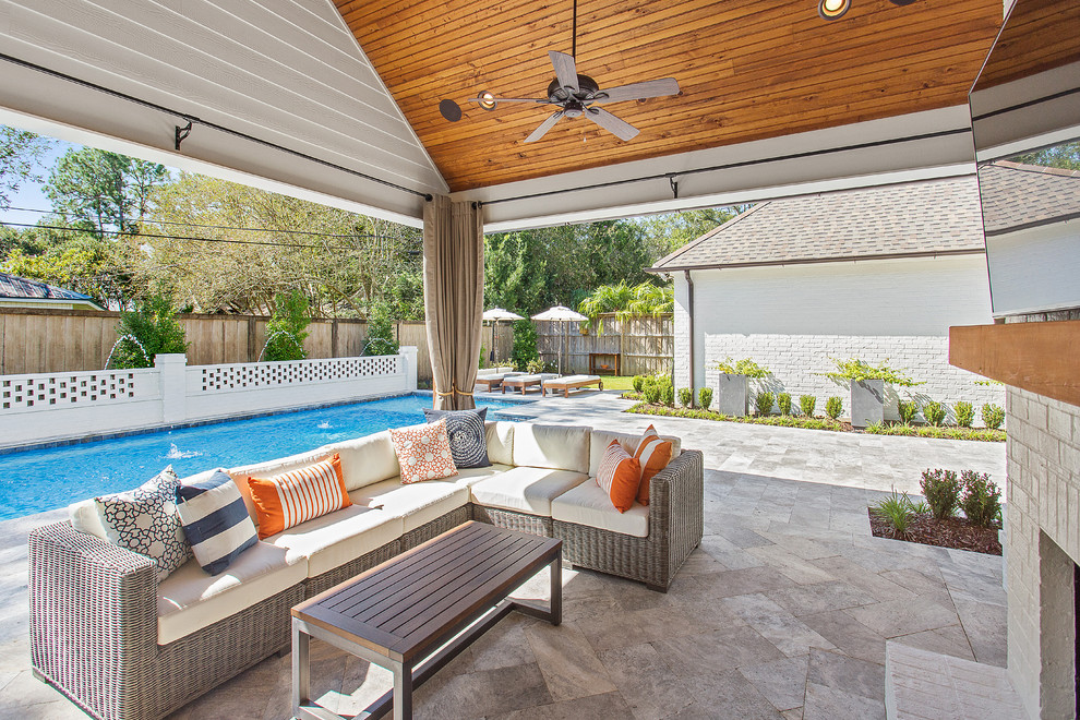 This is an example of a mid-sized contemporary backyard patio in New Orleans with a fire feature, natural stone pavers and a roof extension.