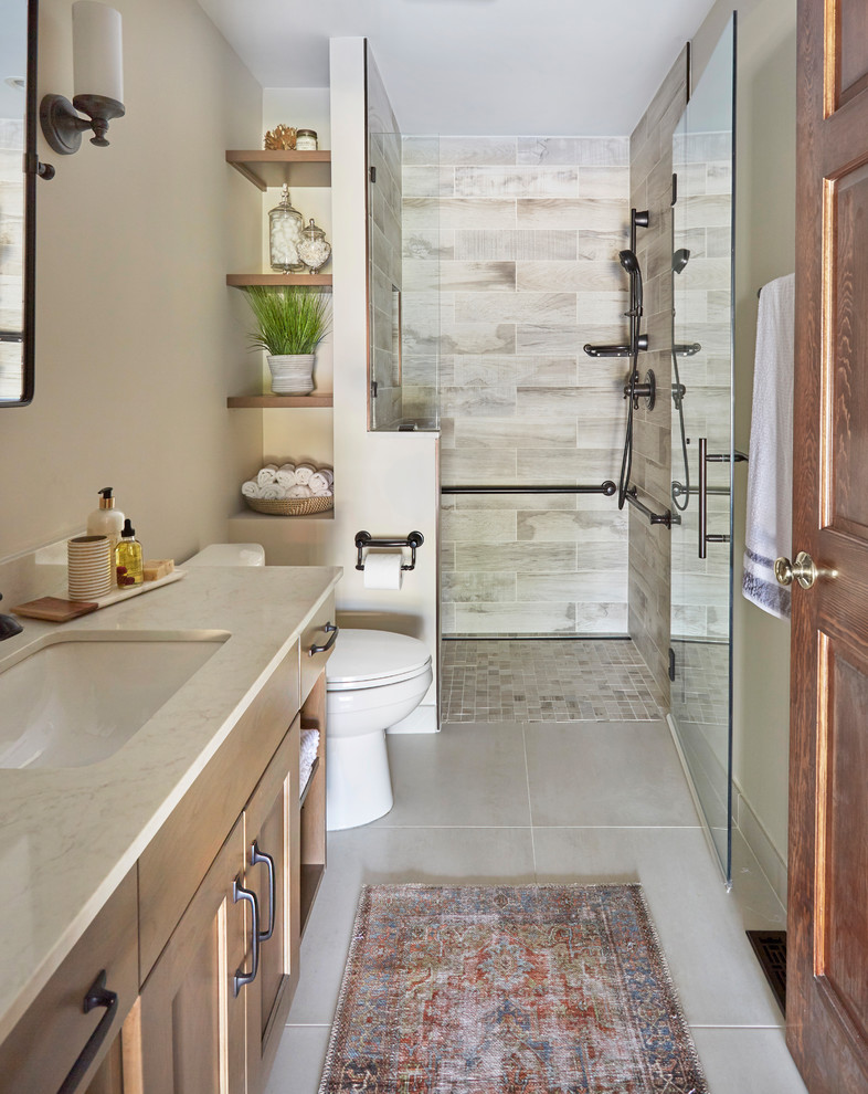 Inspiration for a small arts and crafts 3/4 bathroom in Chicago with shaker cabinets, light wood cabinets, an alcove shower, a two-piece toilet, multi-coloured tile, porcelain tile, beige walls, porcelain floors, an undermount sink, engineered quartz benchtops, grey floor, a hinged shower door and grey benchtops.