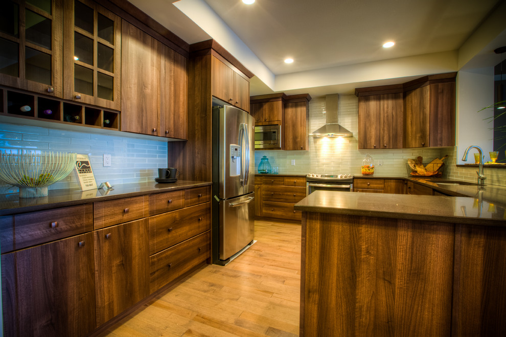 Example of a mid-sized u-shaped medium tone wood floor enclosed kitchen design in Edmonton with an undermount sink, flat-panel cabinets, medium tone wood cabinets, gray backsplash, glass tile backsplash, stainless steel appliances and no island