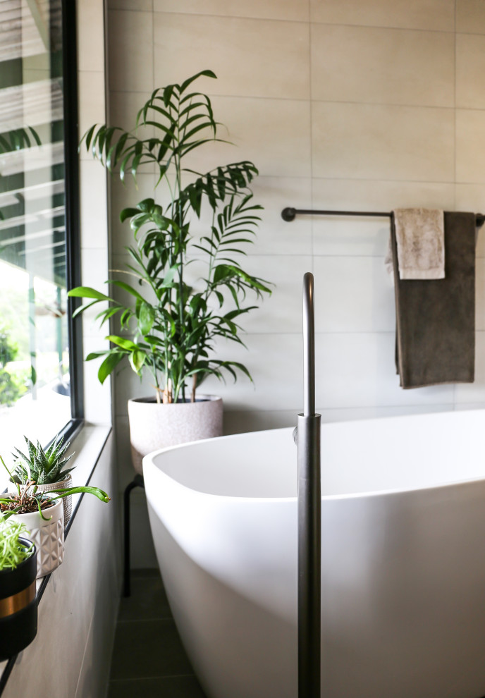 Photo of a large contemporary master bathroom with furniture-like cabinets, dark wood cabinets, a freestanding tub, an open shower, a one-piece toilet, beige tile, ceramic tile, white walls, ceramic floors, a vessel sink, soapstone benchtops, multi-coloured floor, green benchtops, a niche, a single vanity, a floating vanity, vaulted and planked wall panelling.
