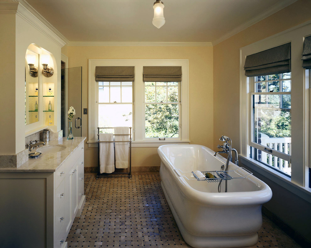 This is an example of a traditional bathroom in Seattle with a freestanding tub and marble benchtops.